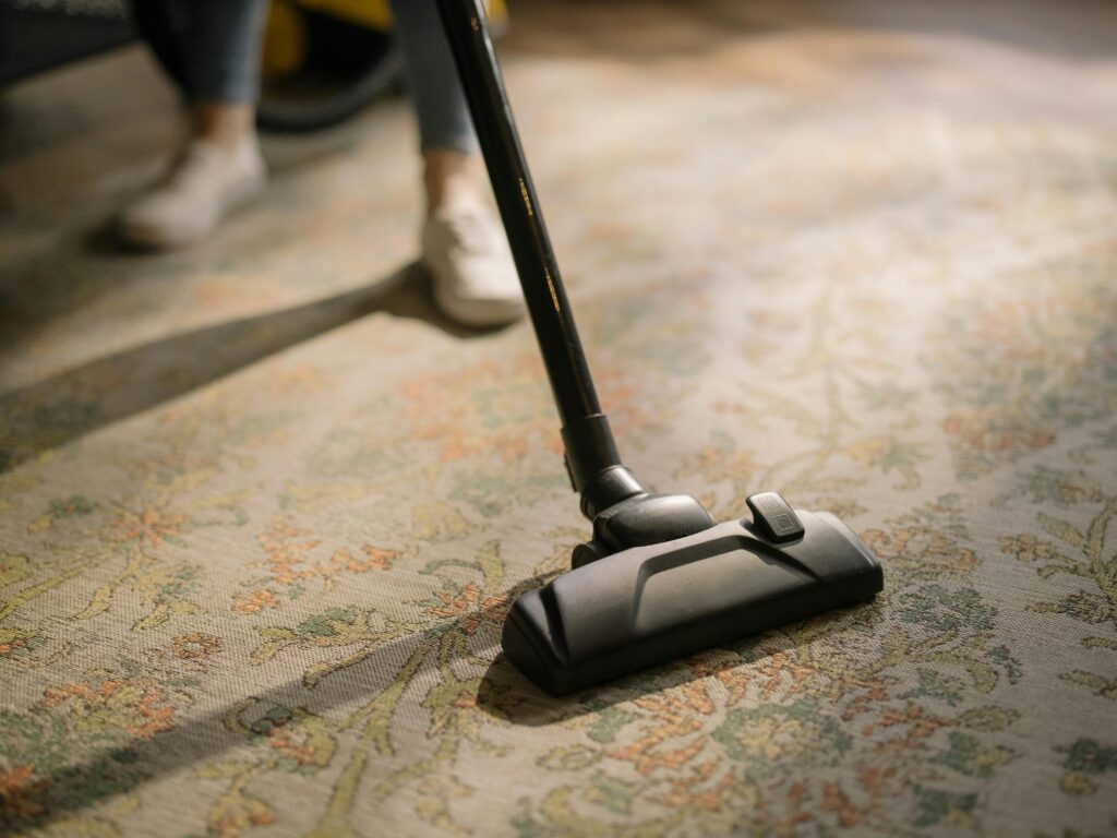 Technician vacuuming a carpet to remove dirt.